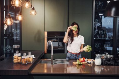 Gündüz vakti mutfakta sağlıklı yiyecekler hazırlayan günlük kıyafetlerle güzel bir esmer kız..