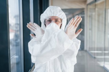 Virüs hareketini durdur. Laboratuvar önlüklü, koruyucu gözlüklü ve maskeli kadın doktor içeride dikiliyor..