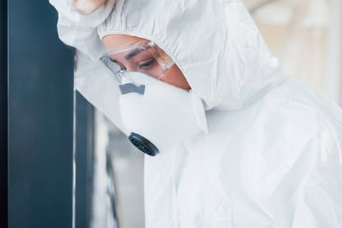Kötü ve hasta hissettiriyor. Laboratuvar önlüklü, koruyucu gözlüklü ve maskeli kadın doktor içeride dikiliyor..