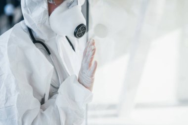 Kötü ve hasta hissettiriyor. Laboratuvar önlüklü, koruyucu gözlüklü ve maskeli kadın doktor içeride dikiliyor..