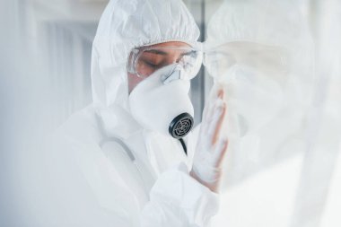 Kötü ve hasta hissettiriyor. Laboratuvar önlüklü, koruyucu gözlüklü ve maskeli kadın doktor içeride dikiliyor..