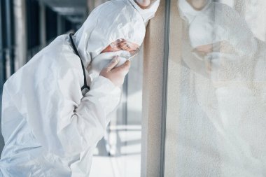 Kötü ve hasta hissettiriyor. Laboratuvar önlüklü, koruyucu gözlüklü ve maskeli kadın doktor içeride dikiliyor..