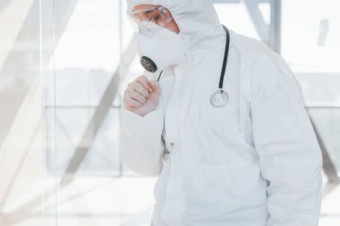 Kötü ve hasta hissettiriyor. Laboratuvar önlüklü, koruyucu gözlüklü ve maskeli kadın doktor içeride dikiliyor..