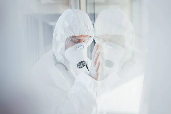 感觉很糟糕很恶心穿着实验室外套 防护眼镜和面罩站在室内的女医生科学家 — 图库照片
