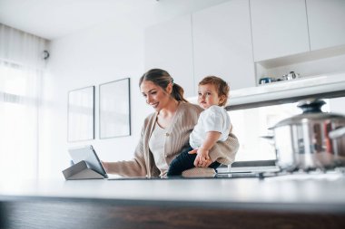 Kadın blogcu anne çocuğuyla birlikte hafta sonu evde tablet kullanıyor..