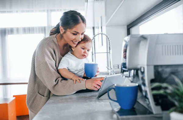 Kadın blogcu anne çocuğuyla birlikte hafta sonu evde tablet kullanıyor..