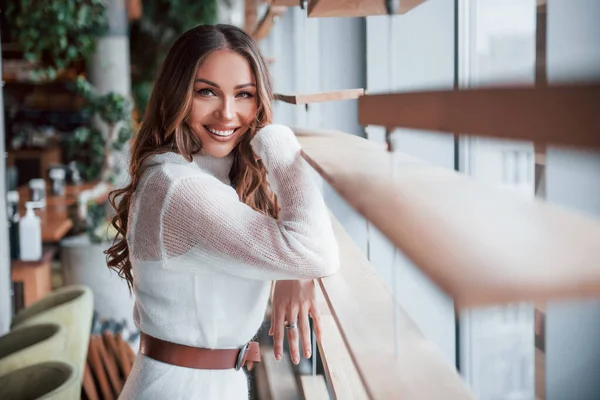 Pencerelerin yanında beyaz elbiseli muhteşem bir kadın duruyor..