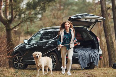 Neşeli kız köpeğiyle birlikte güz ya da bahar mevsiminde ormanda yürüyüşe çıkar..