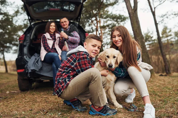 Onnellinen Perhe Istuu Pitää Hauskaa Koiransa Kanssa Lähellä Modernia Autoa — kuvapankkivalokuva