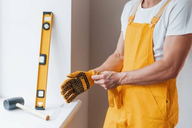 Sarı üniformalı tamirci içeride çalışmaya hazırlanıyor. Ev yenileme konsepti.