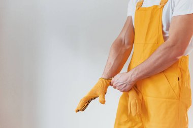 Handyman in yellow uniform preparing for work indoors. House renovation conception.