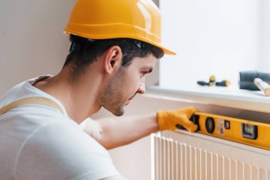 Handyman in yellow uniform installing new battery. House renovation conception.