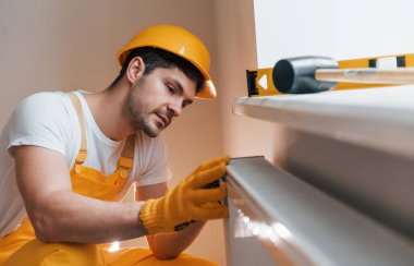 Handyman in yellow uniform installing new battery. House renovation conception.