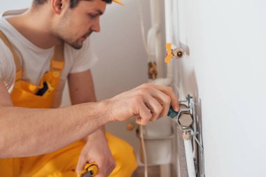 Handyman in yellow uniform works indoors. House renovation conception. Installing new device.