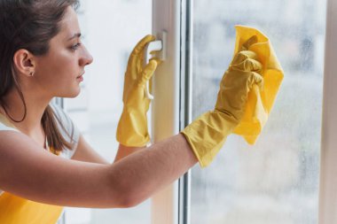 Housewife in yellow uniform cleaning windows. House renovation conception.