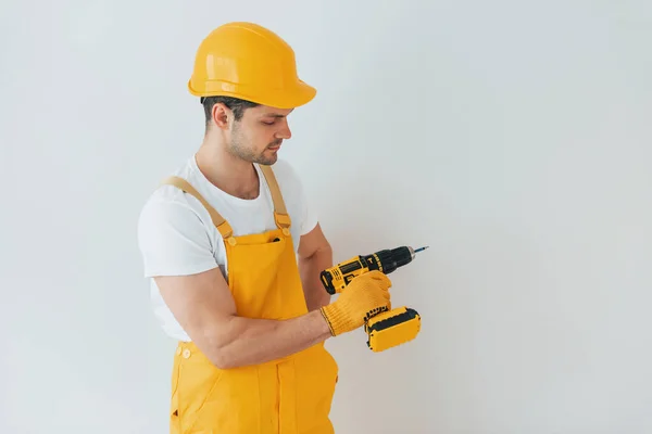 Handyman Uniforme Amarelo Contra Parede Branca Com Chave Fenda Automática — Fotografia de Stock