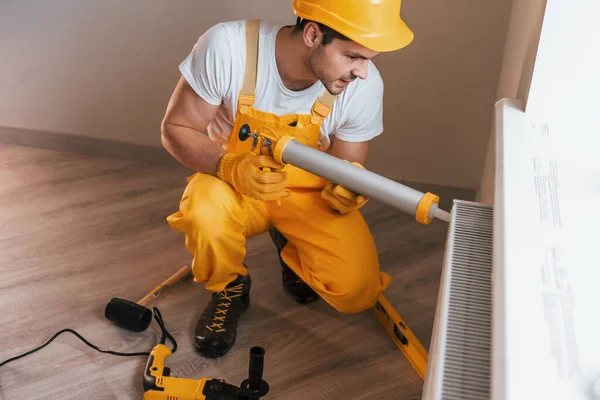 Handyman Yellow Uniform Works Indoors Heat Battery Using Special Tool — Zdjęcie stockowe