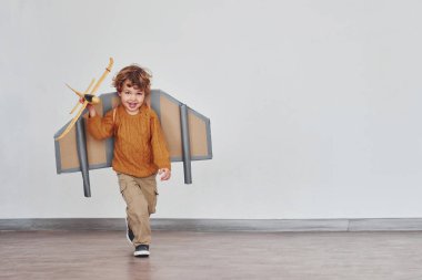 İçinde oyuncak uçak olan retro pilot üniformalı küçük bir çocuk..