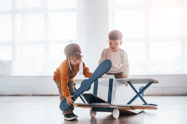 Retro Pilot Üniformalı Iki Küçük Çocuk Içeride Oyuncak Uçakla Eğleniyor — Stok fotoğraf