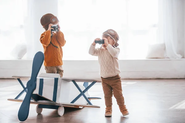 Retro Pilot Üniformalı Iki Küçük Çocuk Içeride Oyuncak Uçakla Eğleniyor — Stok fotoğraf