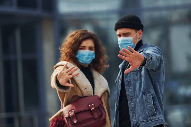 Koruyucu maskeli bir çift, karantina zamanında iş binasının yakınında şehir dışında yürüyüş yapıyor. Koronavirüs kavramı.