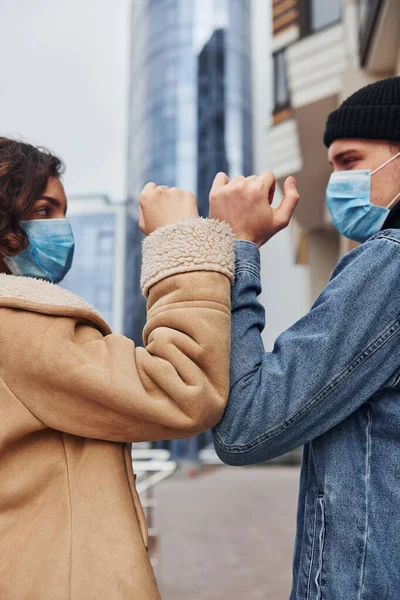 Karantina zamanında iş yerinin yakınında koruyucu maskeli bir çift birbirini selamlıyor. Koronavirüs kavramı.