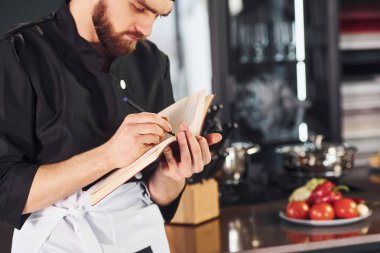 Mutfakta not defteriyle duran üniformalı profesyonel aşçı..