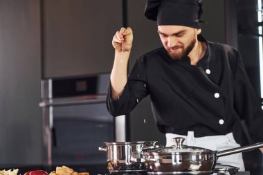 Ekipman kullanarak. Üniformalı profesyonel aşçı mutfakta sebzelerle çalışıyor..