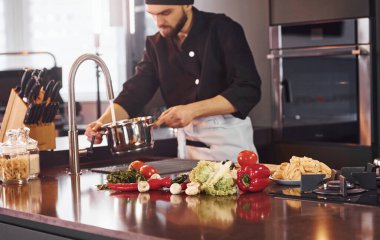 Sebze. Üniformalı profesyonel aşçı mutfakta çalışıyor..