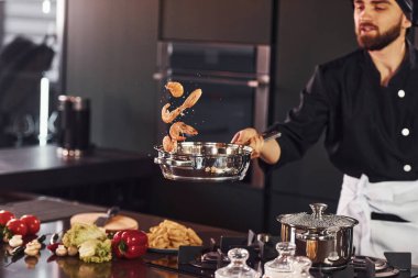 Profesyonel aşçı üniformalı mutfakta yemek pişiriyor..