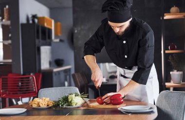 Sebze. Üniformalı profesyonel aşçı mutfakta çalışıyor..