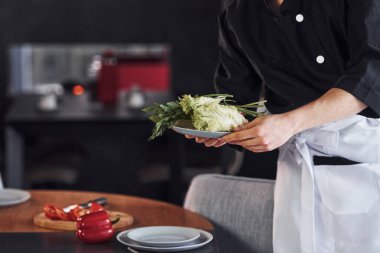 Sebze. Üniformalı profesyonel aşçı mutfakta çalışıyor..
