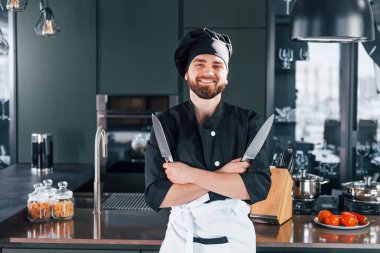 Mutfakta kameraya poz veren, üniformalı genç aşçının portresi..