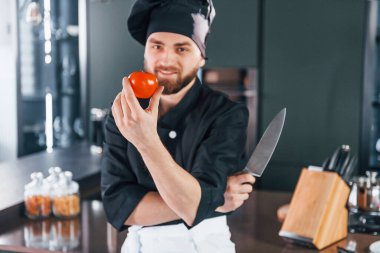 Mutfakta kameraya poz veren, üniformalı genç aşçının portresi..