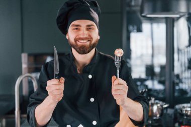 Mutfakta kameraya poz veren, üniformalı genç aşçının portresi..