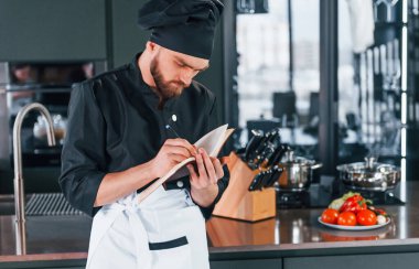 Mutfakta not defteriyle duran üniformalı profesyonel aşçı..