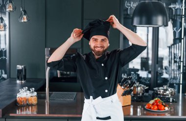 Mutfakta kameraya poz veren, üniformalı genç aşçının portresi..