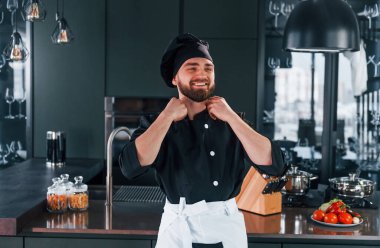 Mutfakta kameraya poz veren, üniformalı genç aşçının portresi..