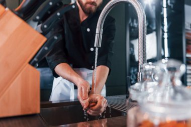 Üniformalı genç aşçı mutfakta ellerini yıkıyor..