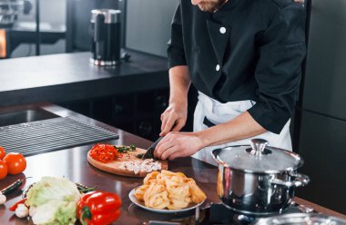 Mutfakta çalışan, üniformalı, profesyonel aşçıya yakından bakın..