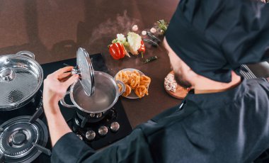 Mutfakta çalışan, üniformalı, profesyonel aşçıya yakından bakın..