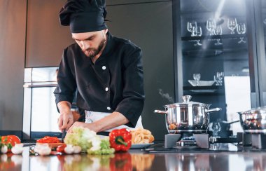 Üniformalı profesyonel aşçı mutfakta çalışıyor..