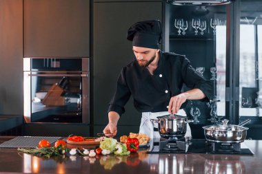 Üniformalı profesyonel aşçı mutfakta çalışıyor..