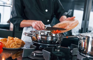 Üniformalı profesyonel aşçı mutfakta çalışıyor..