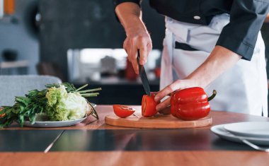 Üniformalı profesyonel aşçı mutfakta salata yapıyor..