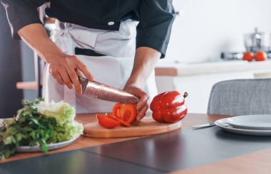 Üniformalı profesyonel aşçı mutfakta salata yapıyor..