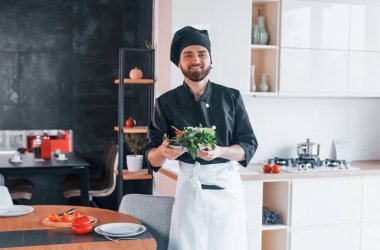 Üniformalı profesyonel aşçı mutfakta salata yapıyor..