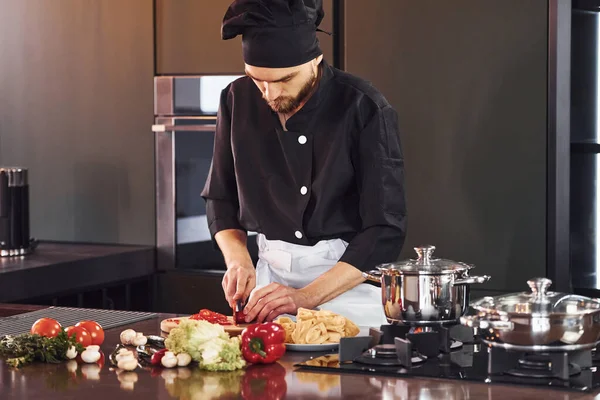 Sebze. Üniformalı profesyonel aşçı mutfakta çalışıyor..