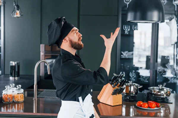 Mutfakta duran, üniformalı, profesyonel aşçının yan görüntüsü..