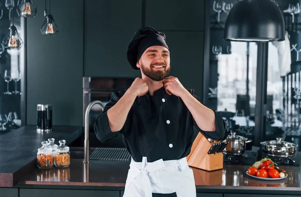 Mutfakta kameraya poz veren, üniformalı genç aşçının portresi..